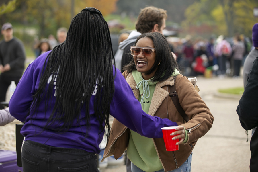 Two people smile and hug outside during a tailgate.