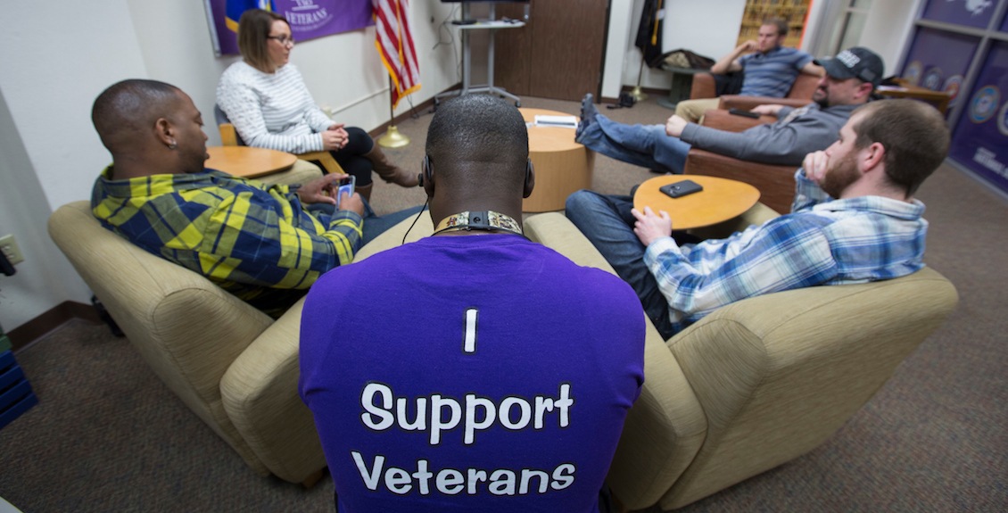 Man sitting while wearing a shirt that reads I Support Veterans