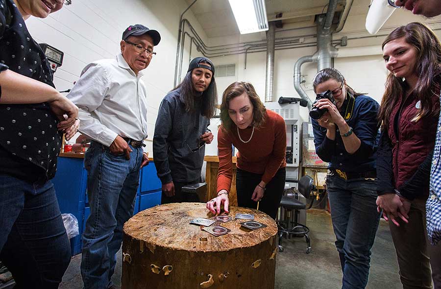 Teresa Faris sits on a table in a jewelry lab.