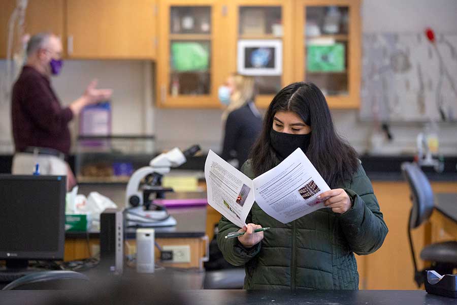 Student standing in a lab reading an in-class exercise.