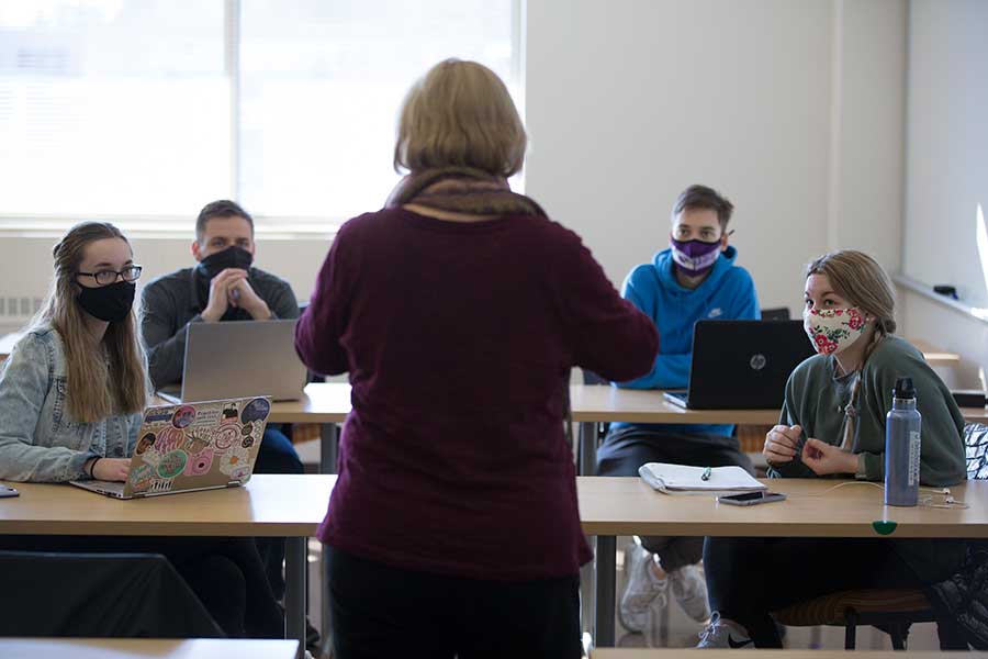 Matthews stands in a classroom full of students with her back to the camera.