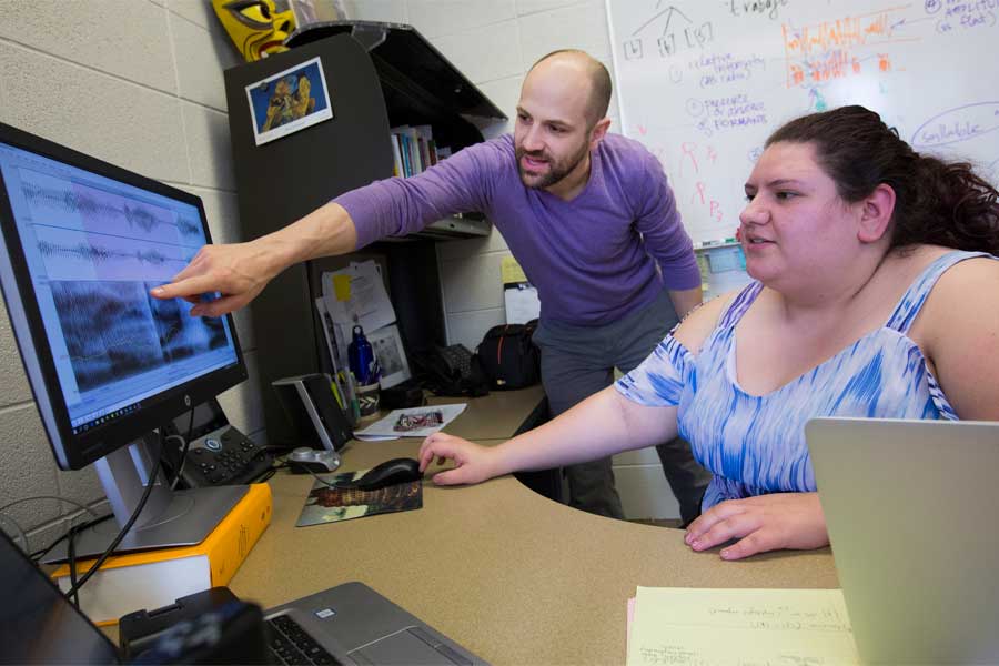 Nate Maddux works with a student at a computer.