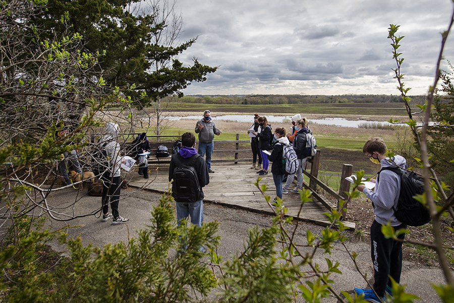 Students stand outside watching a stormy sky.