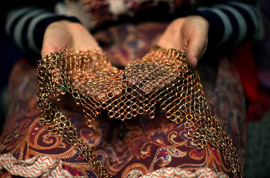 Two hands hold a large, looped, metal necklace.