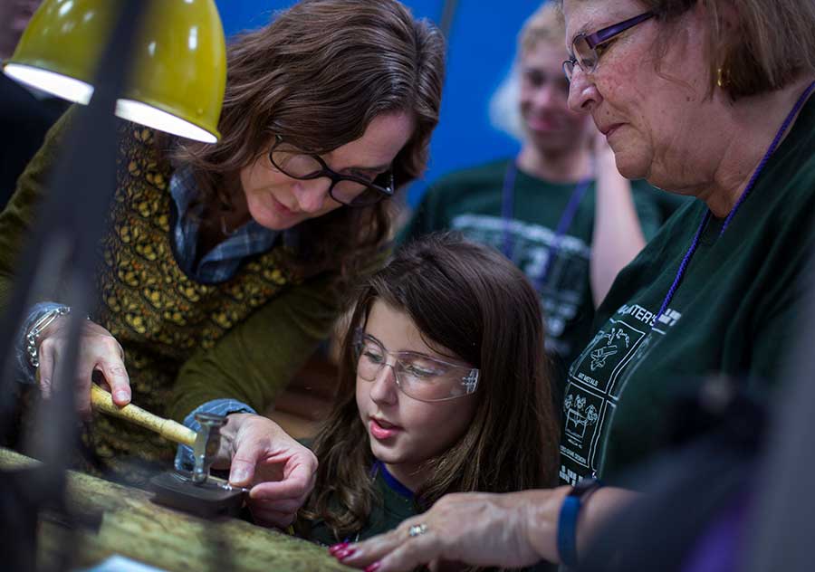 Teresa Faris helps a child and her with a heart-shaped pewter medallion.