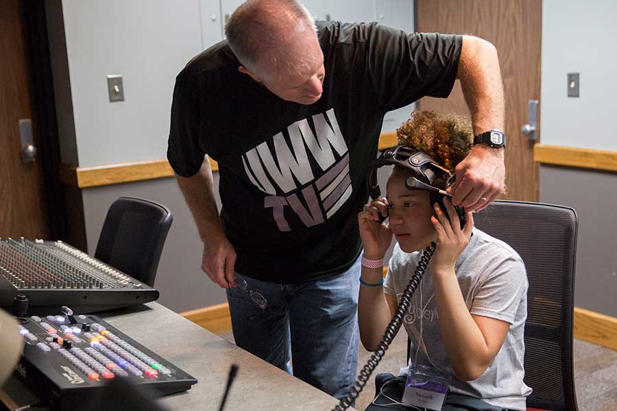 Jim Mead helps a CyberGirlz camper with a headset in the control room.