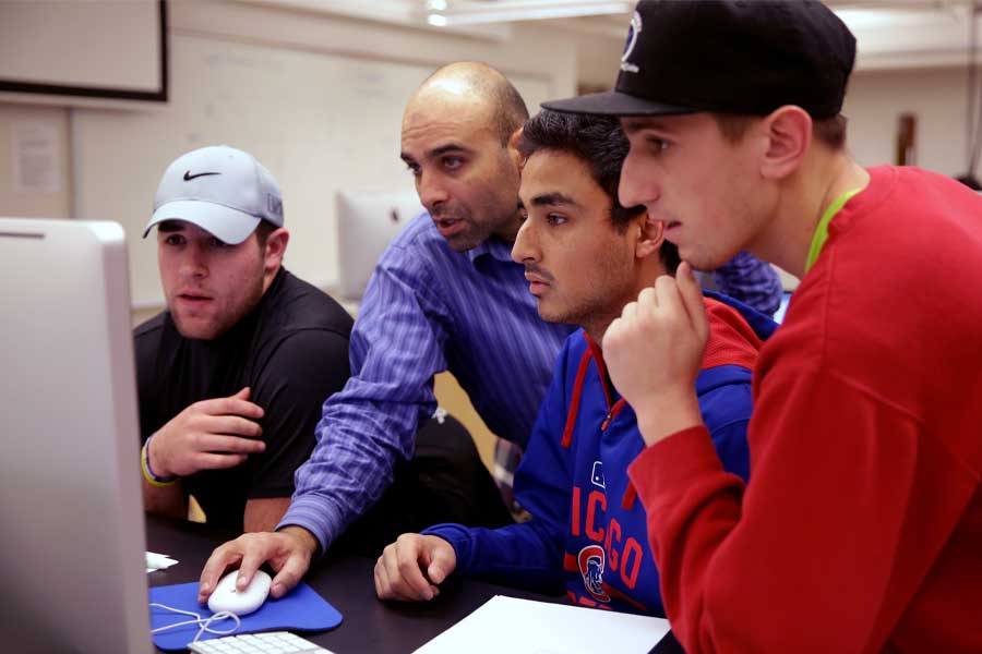 Jalal Nawash works with students on a computer.