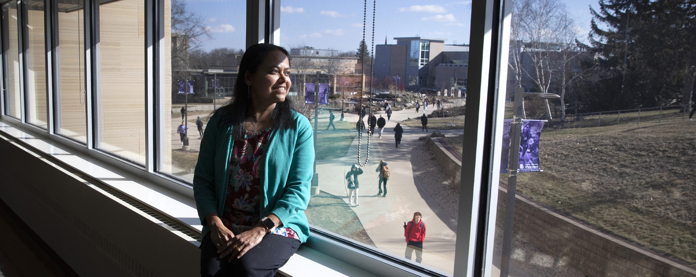 Rashiqa Kamal sits indoors on a windowsill and looks outside.