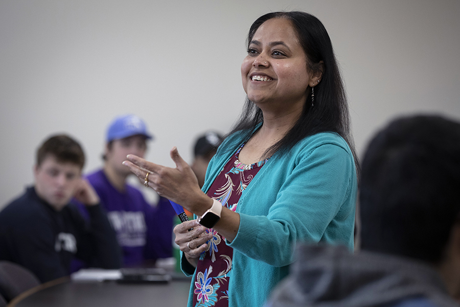 Rashiqa Kamal smiles and stands with her arms extended during a lecture.