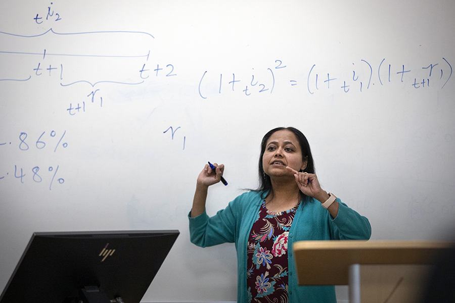 Rashiqa Kamal smiles stands in front of a white board with mathematical equations.