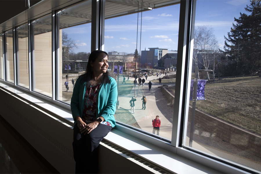 Rashiqa Kamal sits on a windowsill indoors and looks outside.