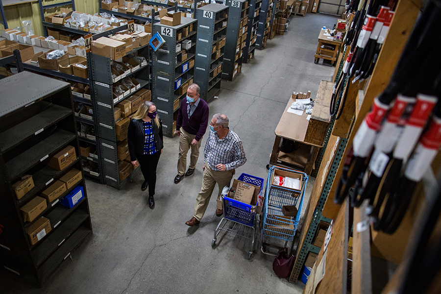 Anna Land walks in a warhouse with two other people