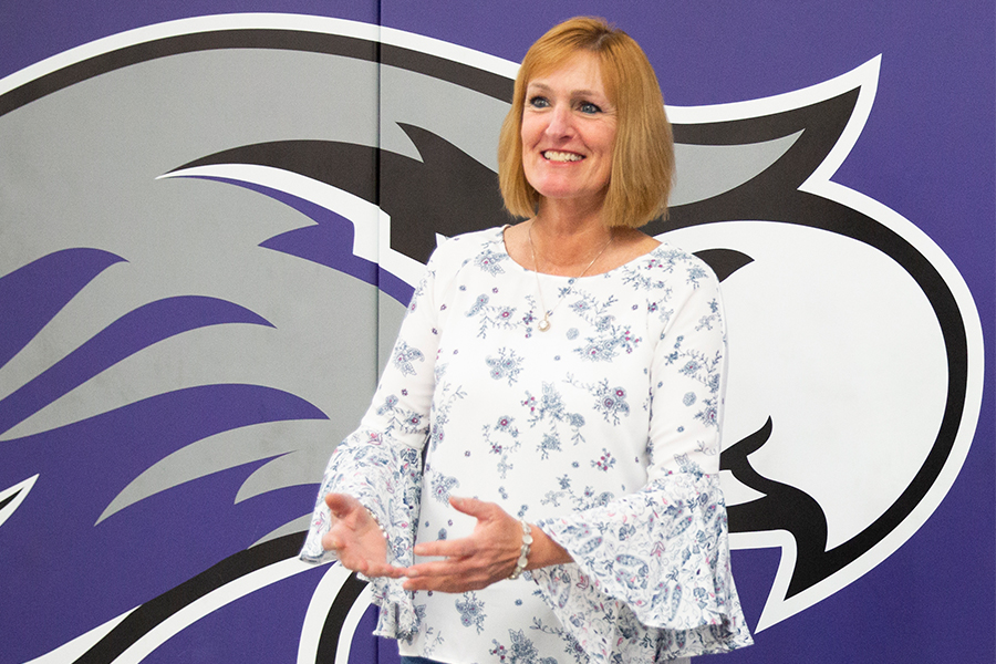 Kathleen Happel stands against a large Warhawk on a wall.