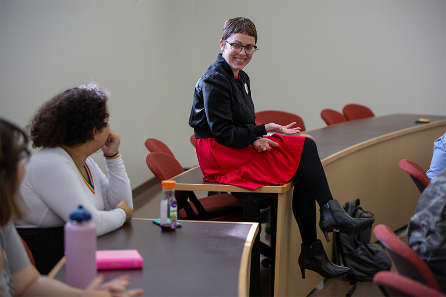 Stepahnie Selvick sits on a table, talking with students.