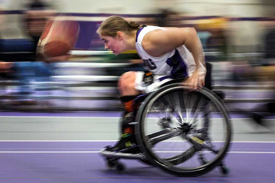 A blurry photo shows how quickly a wheelchair basketball player races to grab a basketball.