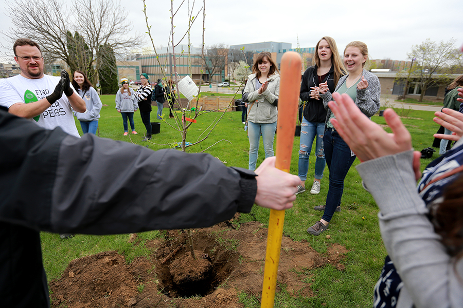 Sustainability Director Wes Enterline, left, applauds volunteers as young fruit trees are planted in the Campus Garden.