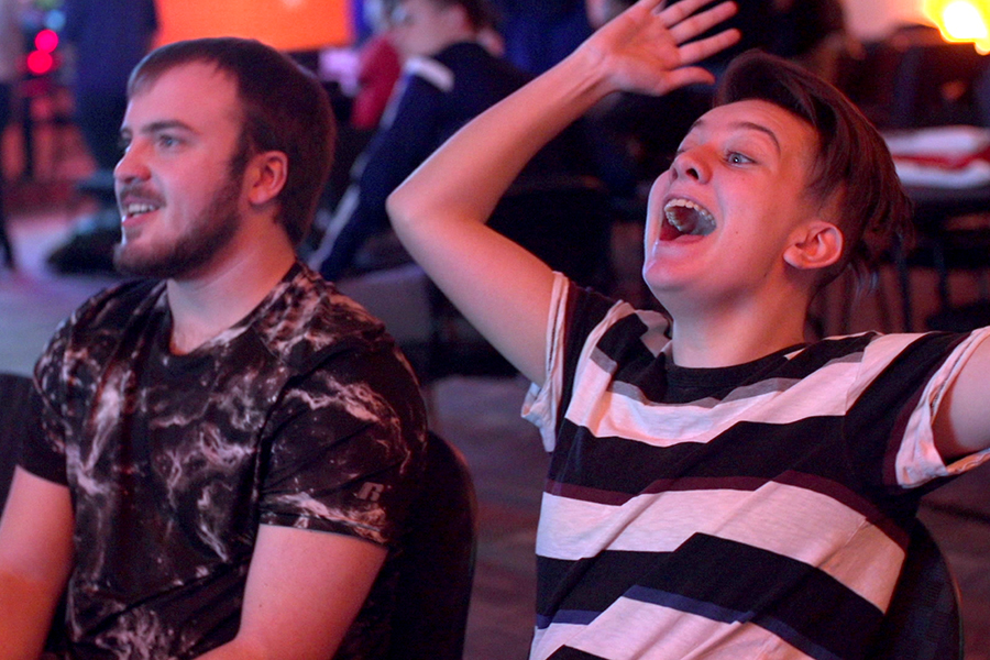 Two students react while playing video games.