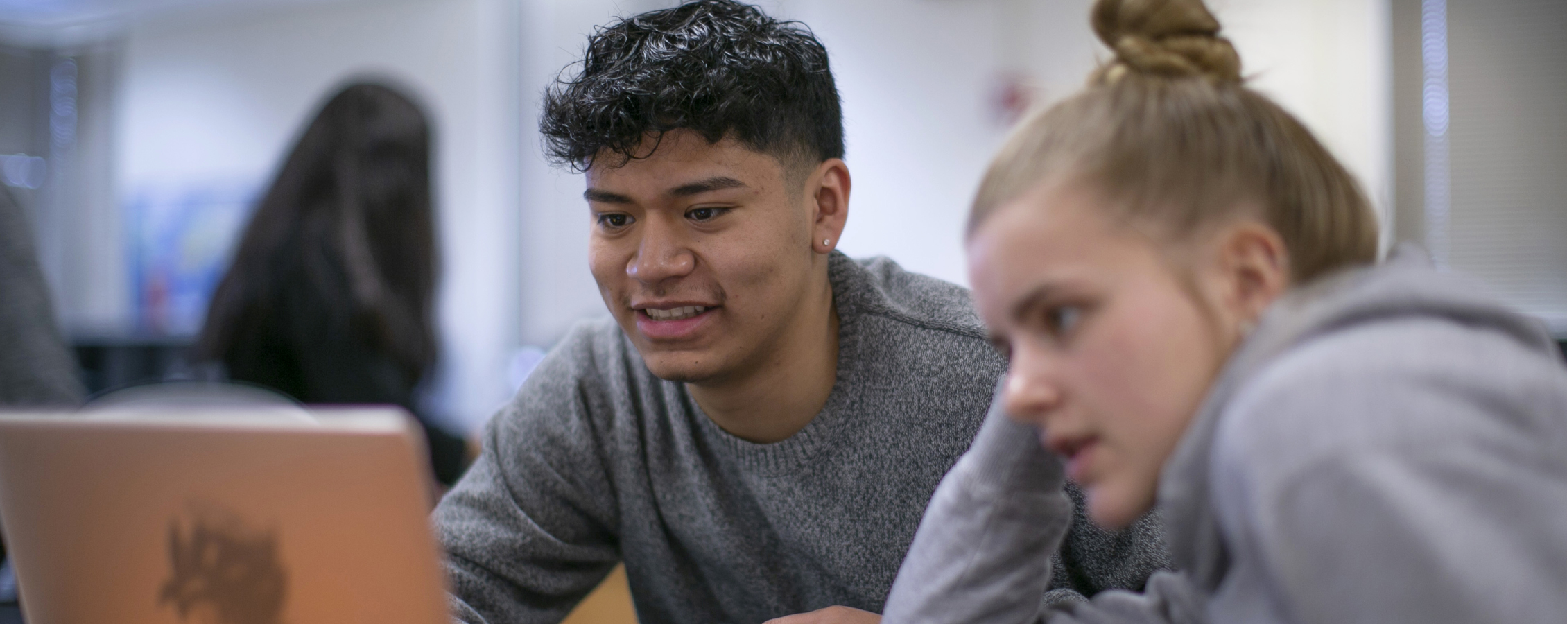 Two students work on a computer.