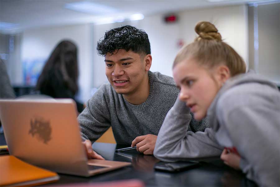 Two students work on a computer.