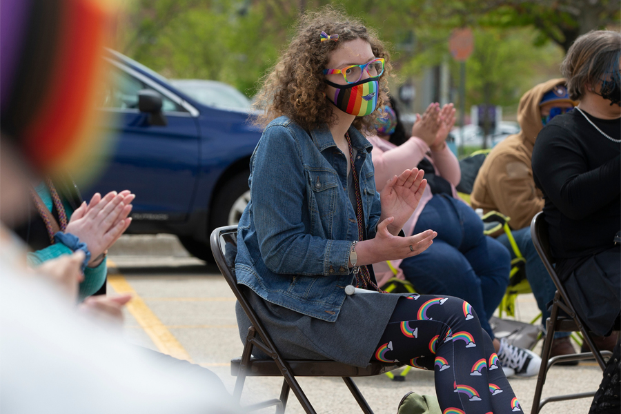 A student sits in a chair outside during the Rainbow Celebration of Excellence event.