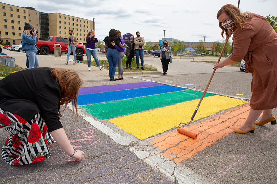 Ashley Barnes-Gilbert paints rainbow colors in a crosswalk on Warhawk Drive.