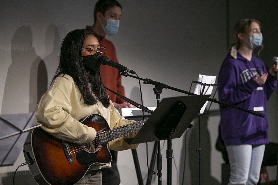 Hannah Keziah Agustin sings on stage with a guitar.