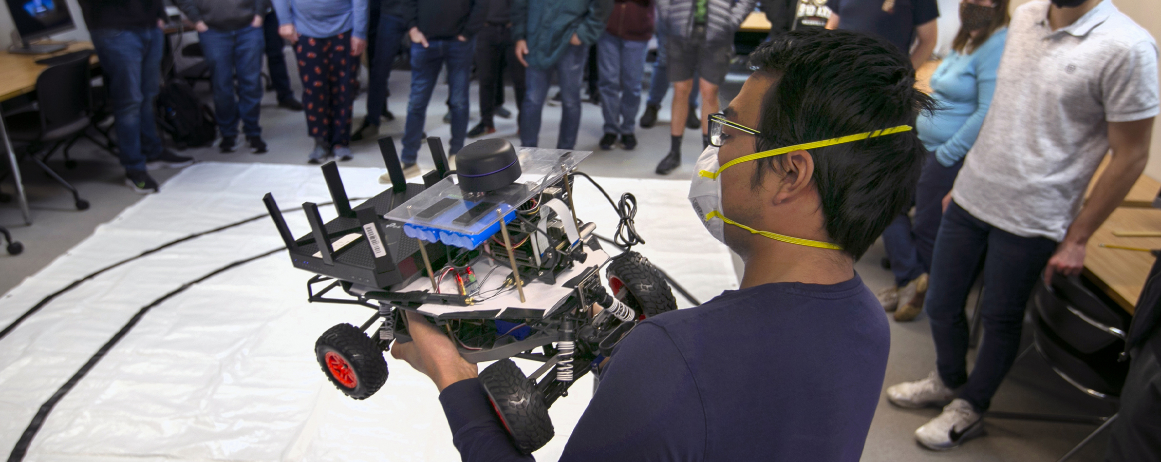 Dr. Sun holds an autonomous car in front of students.