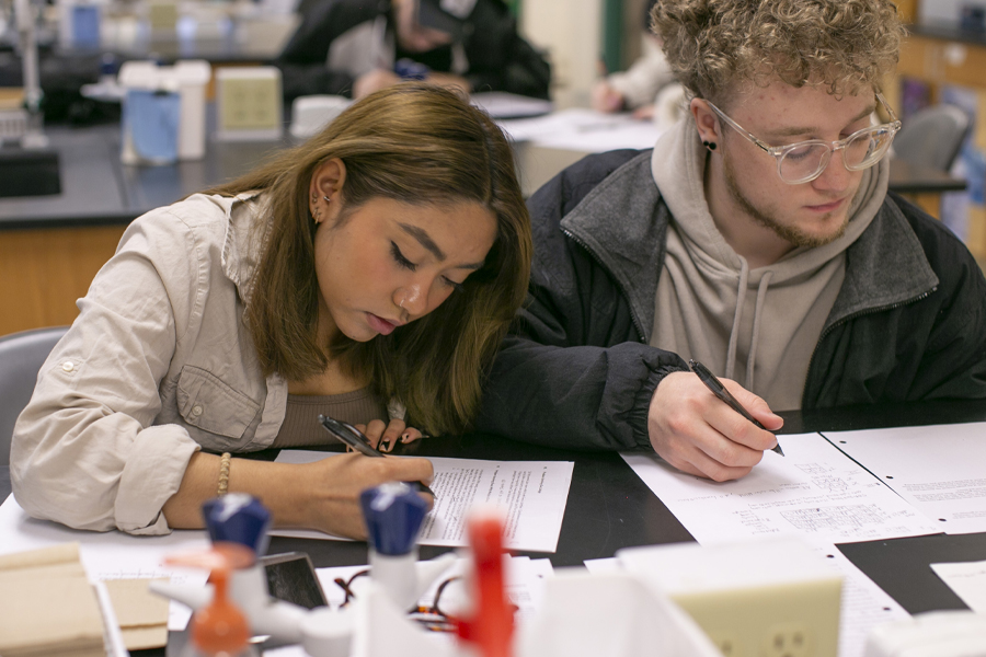 Two students work at a desk.