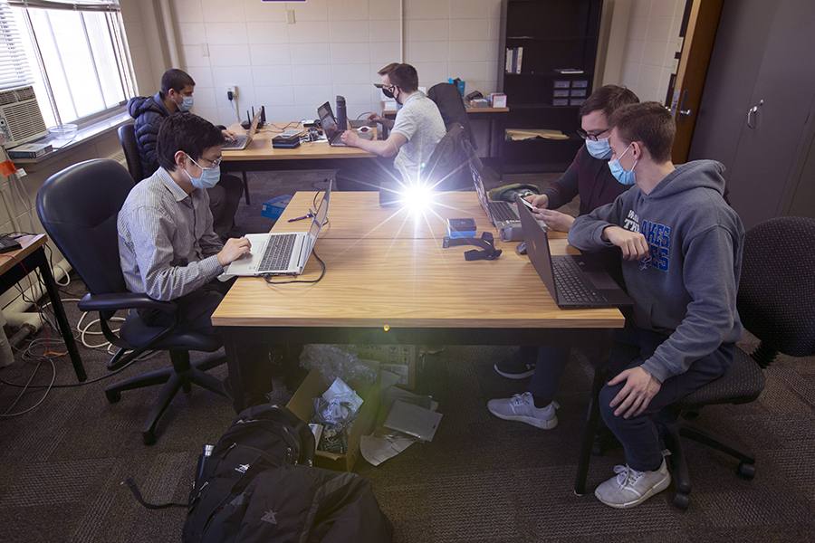 Students work on laptops in a classroom.