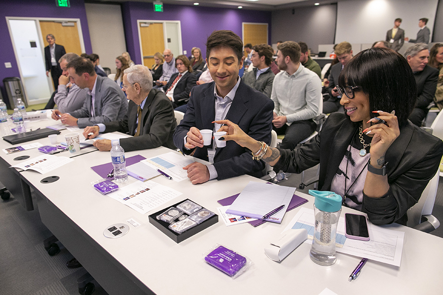 Judges at a business plan competition cheers paper cups.