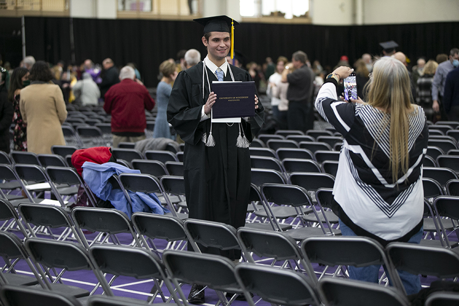 A graduate stands with their diploma.
