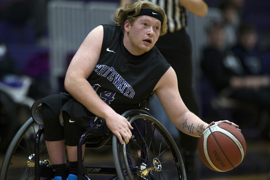 A wheelchair basketball player dribbles the ball.