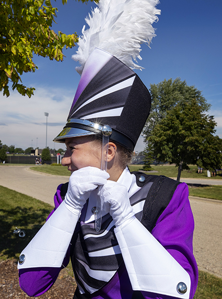 Glenn Hayes stands in Perkins Stadium with a microphone in his hand wearing a purple blazer.