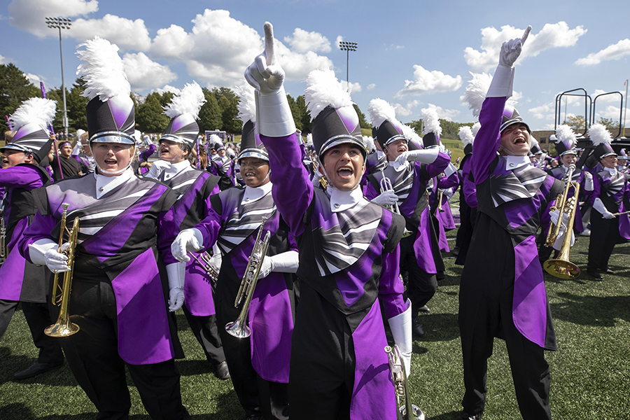 The Marching Band cheers in full uniform on the football field.