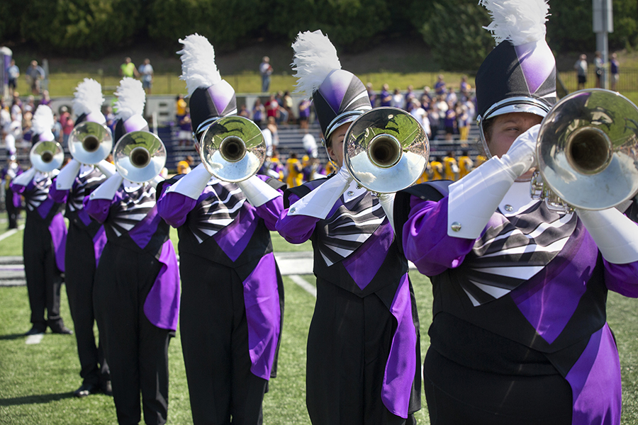The Marching Band trombonists stand together in their new uniforms with their instruments up.