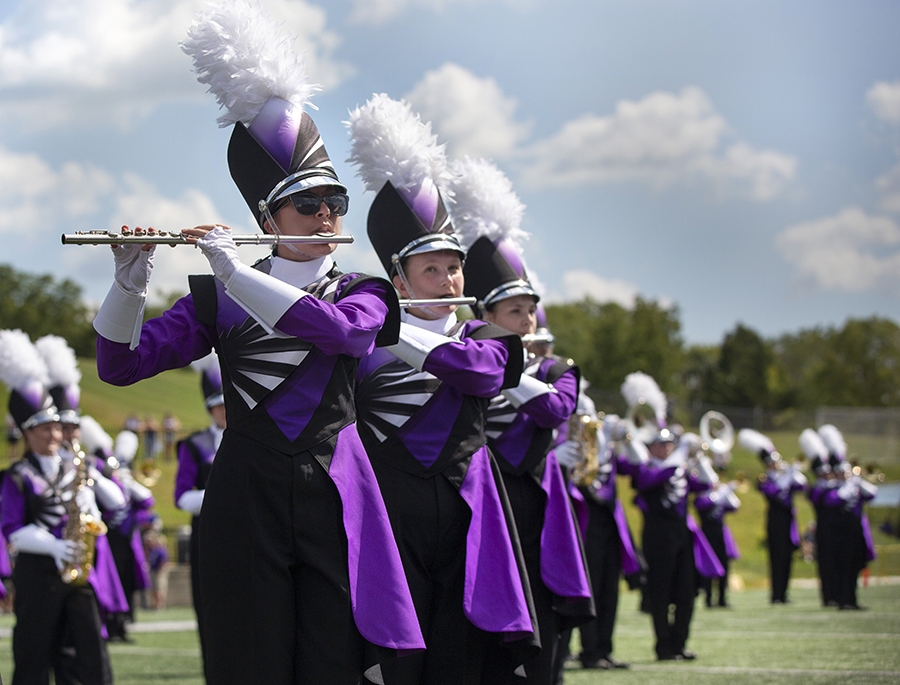 The Marching Band stands together in their new uniforms with their instruments up.