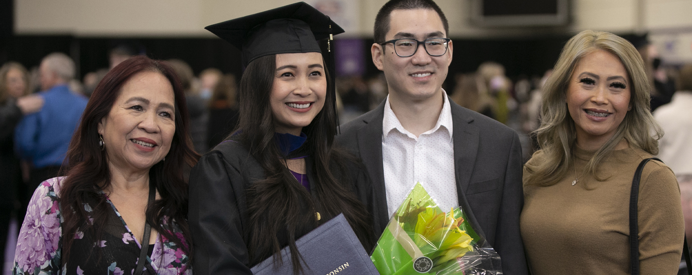 A graduate poses with her family at commencement.