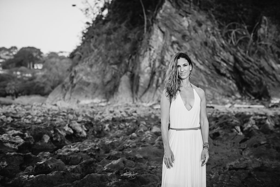 A black and white photo of Jen Rulon standing outside wearing a white dress.