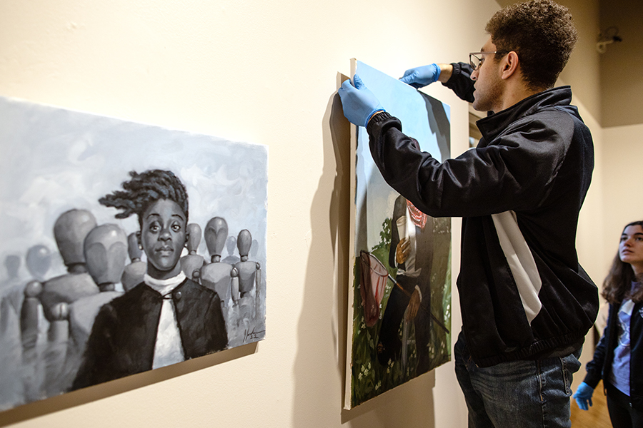 Brian Michael, a media arts and game development student from Sycamore, Illinois, hangs 12 works by painter Jerry Jordan at Roberta's Art Gallery on Jan. 25, 2023.