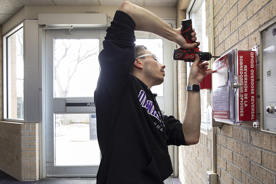 Man installing Narcan box to the wall.