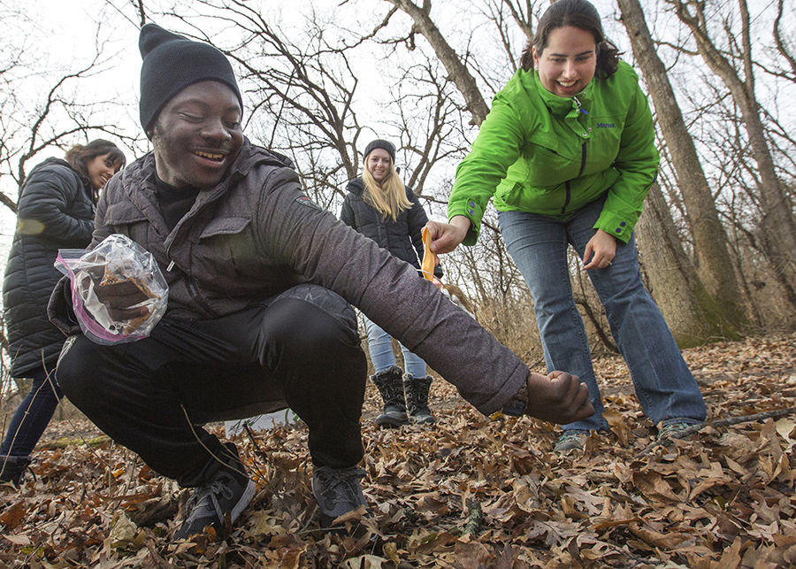 Students are outside in a wooded area collecting research and a mouse is running up the sleeve of a student.