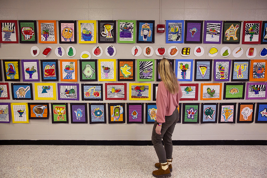 Peterson stands in front of a wall covered in colorful paintings.