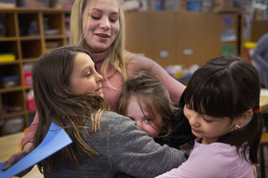 Student hugging several children. 