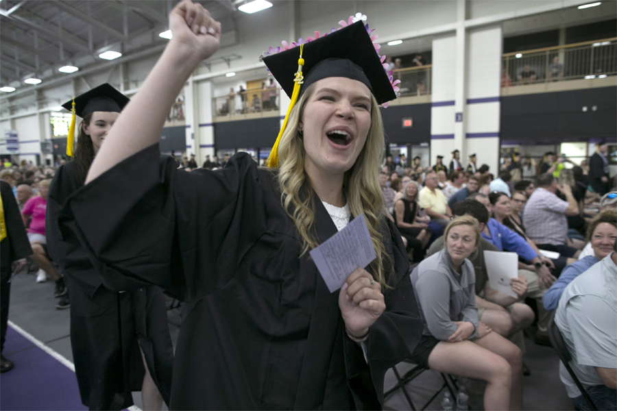 Students wearing cap and gown walking to the stage.