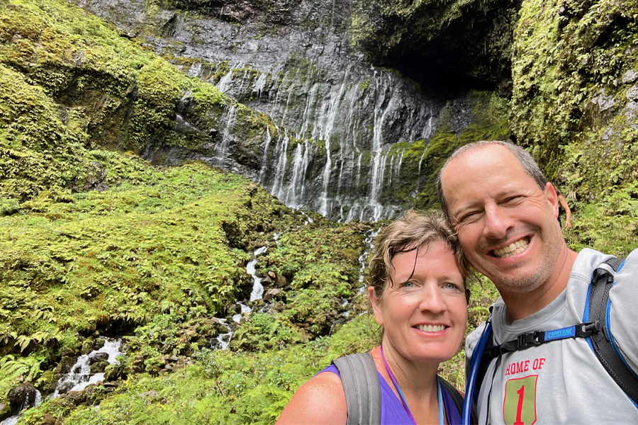 Domitrz and his wife stand in front of a waterfall.