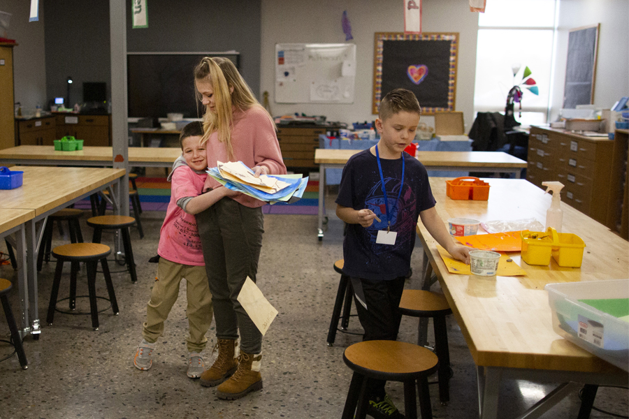 Student hugging students in a classroom.