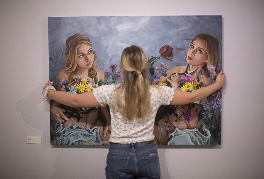 Hollyn hangs one of her paintings on a wall.