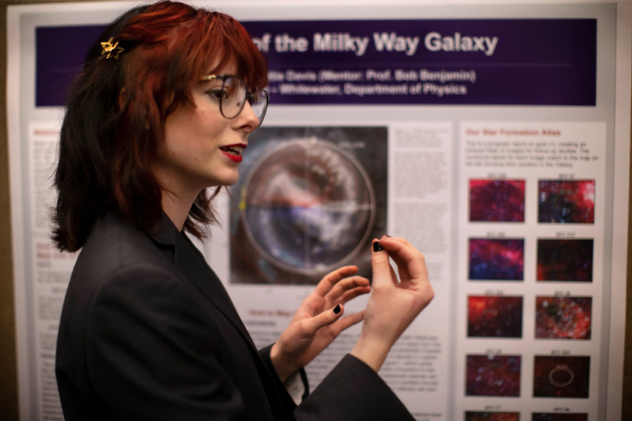 A student presents their research in front of a board that says Milky Way Galaxy.