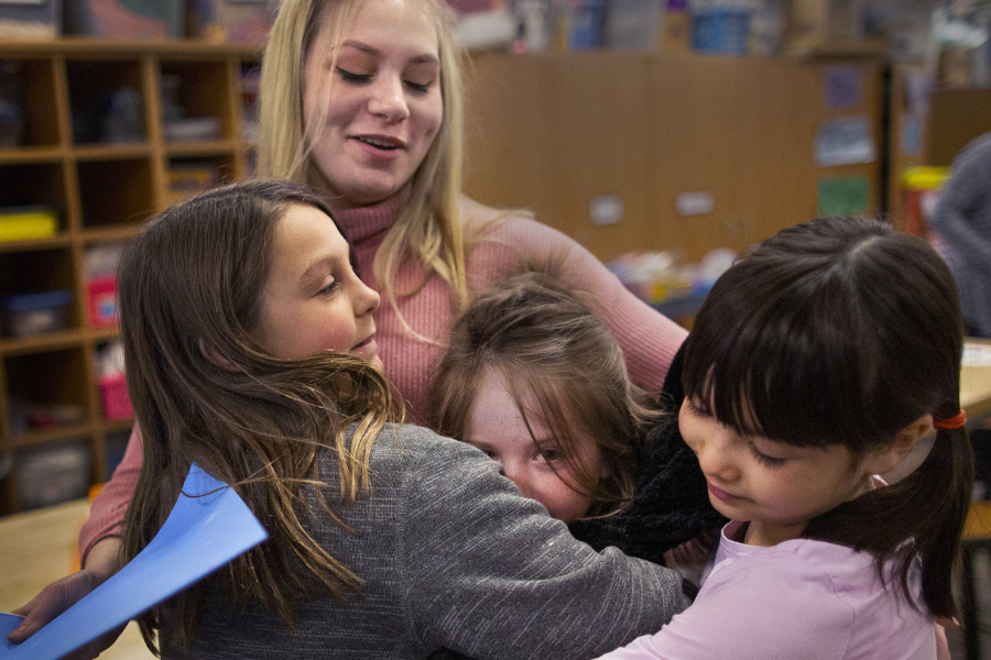 Hollyn Peterson hugs three students.