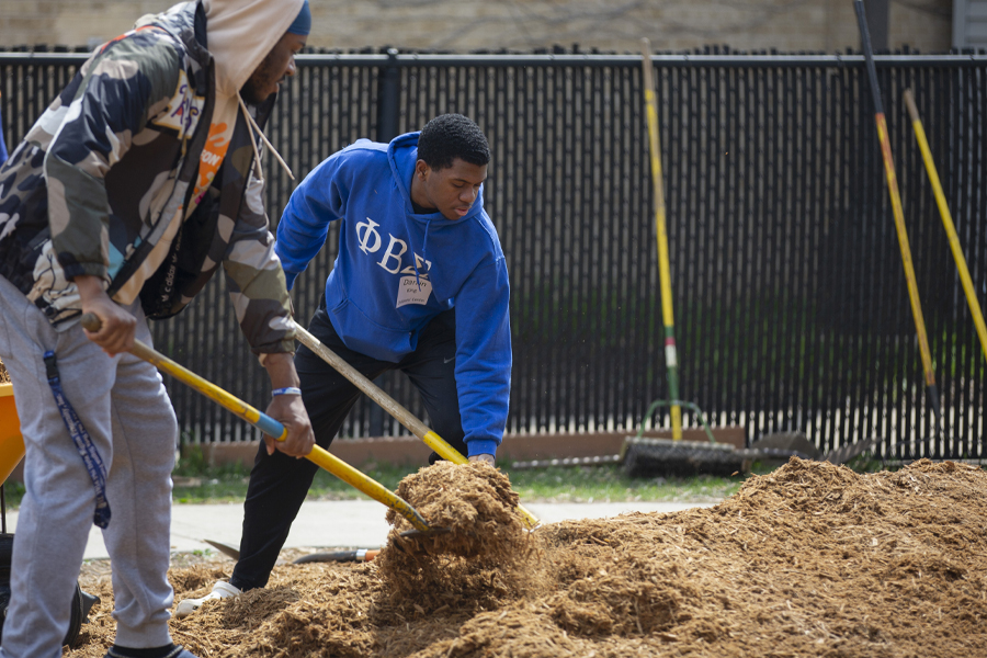 Two students spread mulch outdoors.